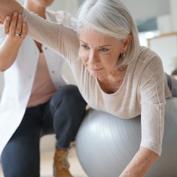 donna anziana durante esercizio fisico con palla medica